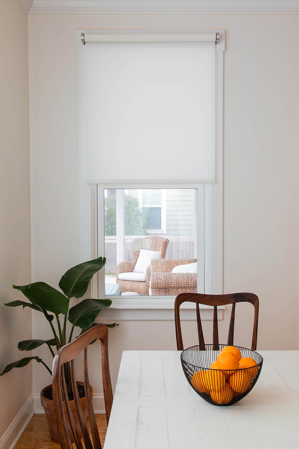 Dining area with motorized roller shade partially covering a window